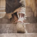 Uma pessoa de sandálias subindo uma escadaria empoeirada.