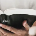 Foto aproximada das mãos de uma pessoa segurando a Bíblia.