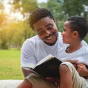 Um pai conversando com seu filho enquanto segura uma Bíblia.