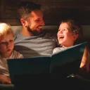 Um pai lendo um livro para seus filhos.