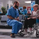 Um médico conversando com uma paciente em cadeira de rodas.