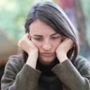 Uma mulher apoiando a cabeça nas mãos.