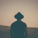 Um homem de chapéu olhando para um campo gramado.