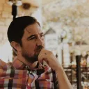 Um homem contemplativo sentado ao ar livre.