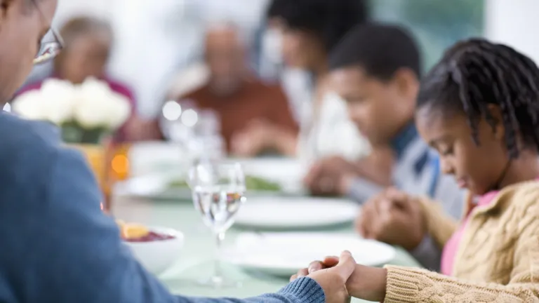 Family group praying before a meal