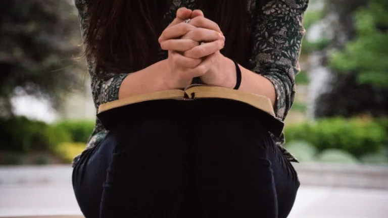 Deus deseja que também nos aproximemos dEle quando estivermos sofrendo. Ele promete nos ajudar se fizermos isso. Deus conforta os abatidos, mas é preciso pedir a Ele por essa ajuda. Uma mulher segurando uma Bíblia.
