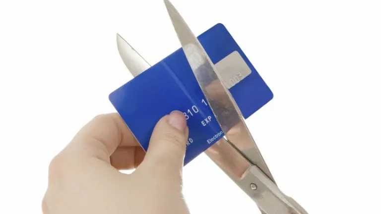 Uma pessoa cortando um cartão de crédito com uma tesoura.
