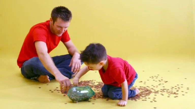 Pai e filho contando moedas de um cofrinho de vidro.