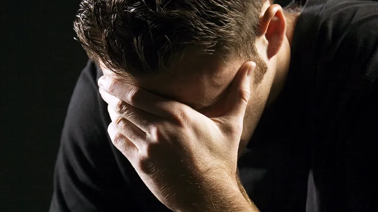 Um jovem segurando a cabeça com as mãos em tristeza ou remorso.