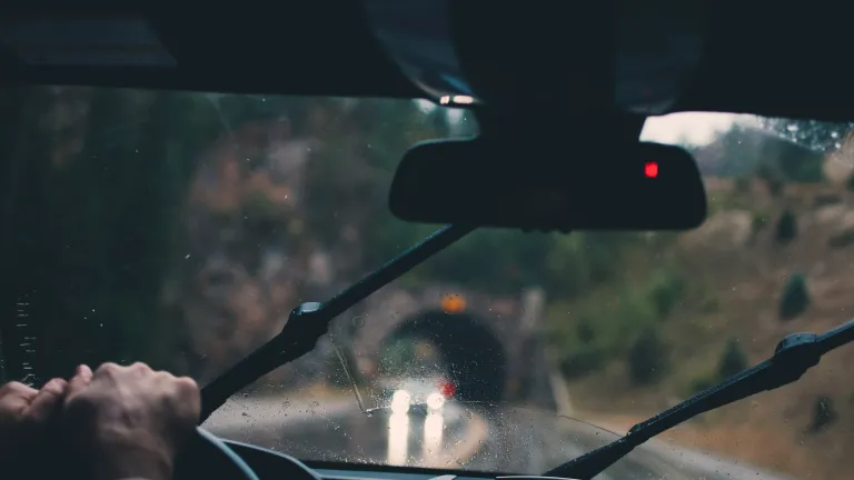 Um homem dirigindo um carro na chuva.