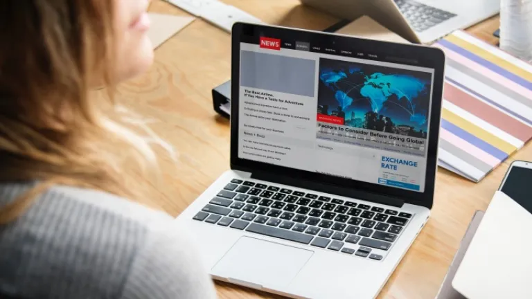 Uma mulher que olha artigos da notícia em um portátil.