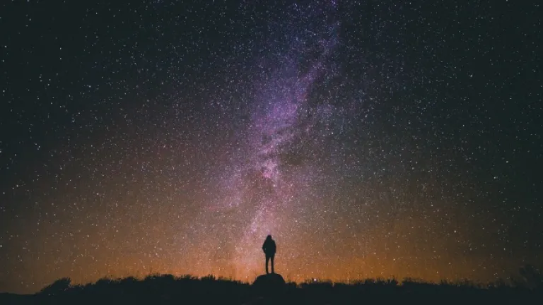 Pelo Espírito somos literalmente herdeiros de Deus e co-herdeiros com Cristo. Nós somos parte da família de Deus. Deus está nos preparando para herdar todas as coisas. Uma pessoa de noite com as estrelas no fundo.