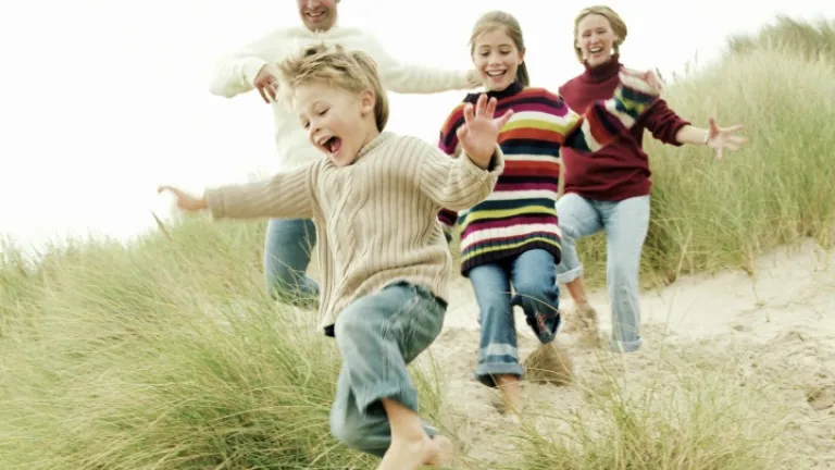Uma família correndo na praia com grama.