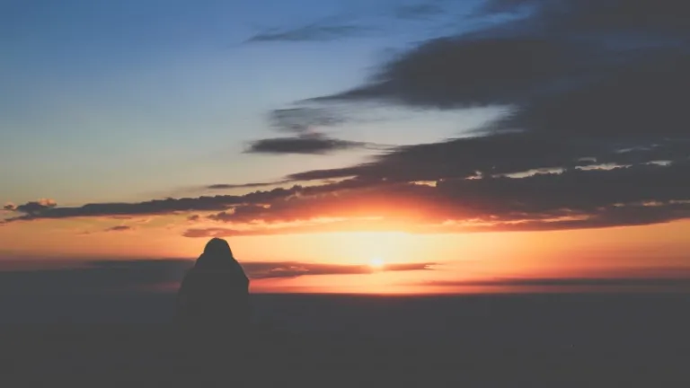 Uma pessoa assistindo o pôr do sol.