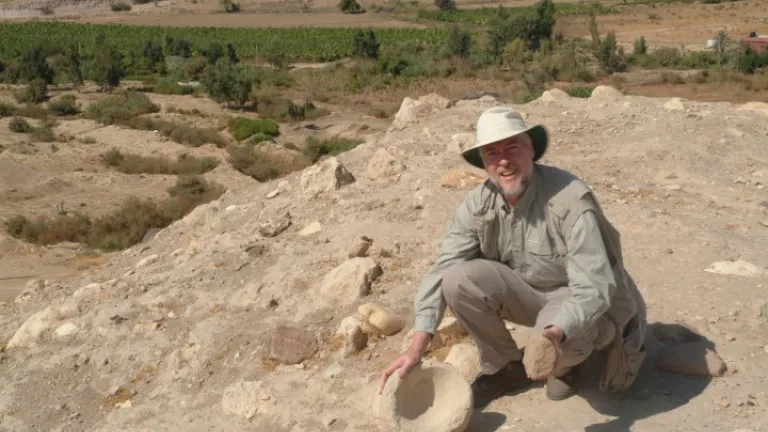 O autor examina um moedor de pedra e uma tigela no Tall el-Hammam antes do início das escavações.