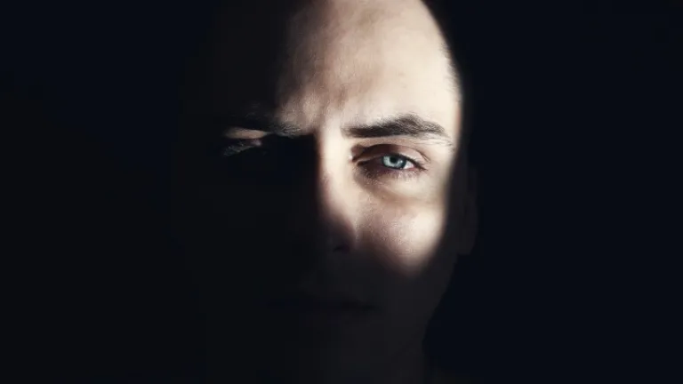 O rosto de um homem oculto nas sombras.