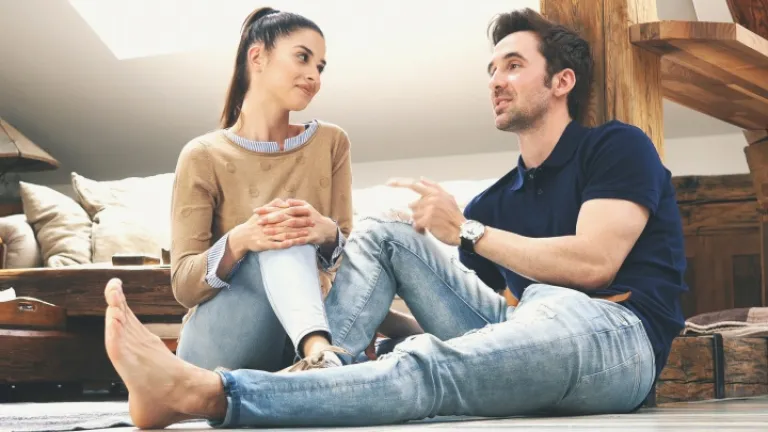Um casal conversando sentado no piso da casa.