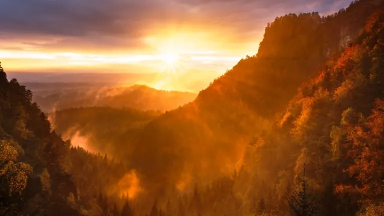 A futura intervenção de Deus levará todas as pessoas a um caminho de vida baseado na justiça, na paz e na cooperação mútua em todas as nações. Um pôr do sol sobre algumas montanhas.