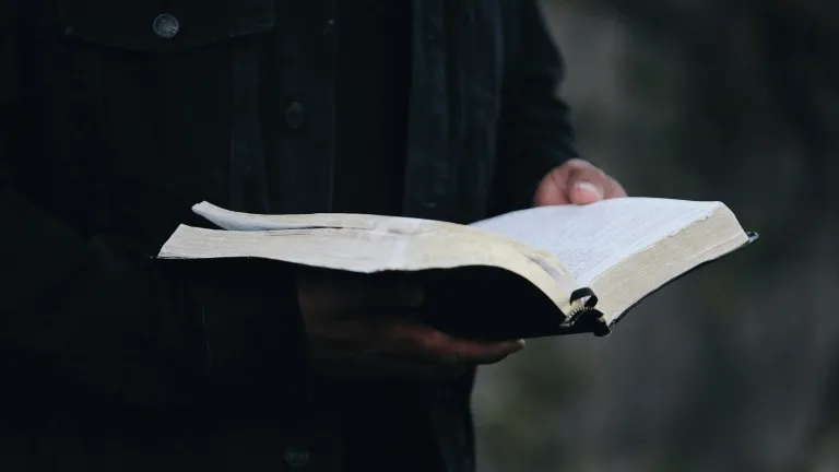Um homem segurando uma Bíblia aberta.
