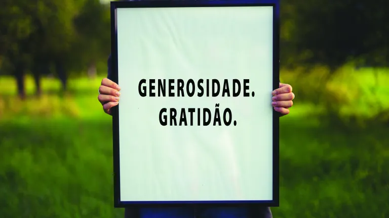Uma pessoa segurando um cartaz escrito: Generosidade. Gratidão.