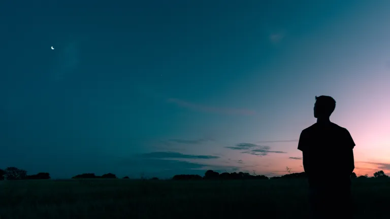Uma pessoa olhando para o pôr do sol.