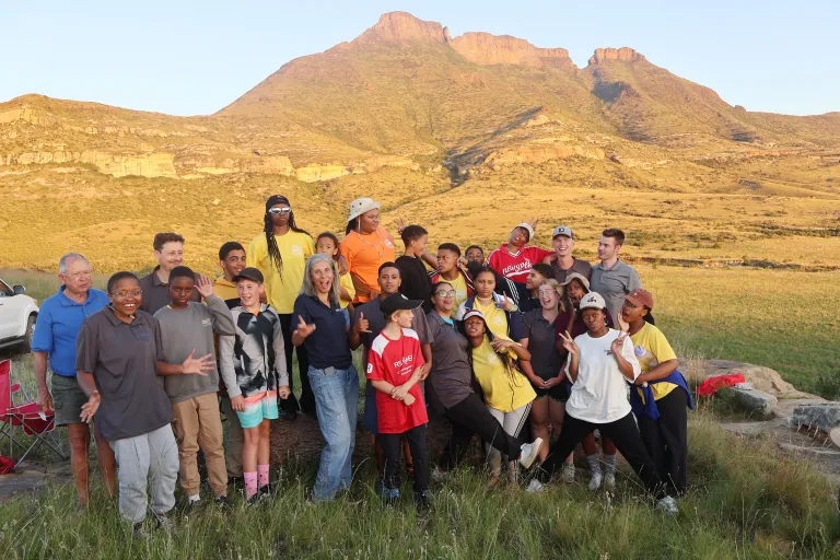 a group of people standing in front of low rolling mountains