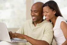 Um jovem casal olhando para um notebook.