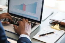 Uma pessoa trabalhando com gráficos financeiros em um laptop.