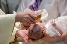 Um bebê sendo aspergido com água.