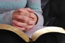 A person's hands on top of a Bible.