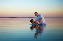 Um homem colocando outro homem debaixo d'água.