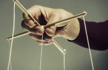 Uma pessoa segurando cordas de uma marionete.