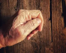 Um velho batendo numa velha porta de madeira.