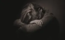 Uma mulher com a sua cabeça em seus braços.