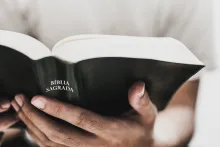 Foto aproximada das mãos de uma pessoa segurando a Bíblia.