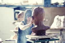 Uma mulher esculpindo um busto.