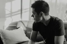 Homem sentado num sofá refletindo sobre sua vida.