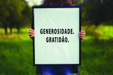 Uma pessoa segurando um cartaz escrito: Generosidade. Gratidão.