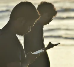 Dois homens olhando para seus celulares.