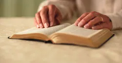 Uma mulher virando as páginas de uma Bíblia.