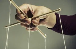 Uma pessoa segurando cordas de uma marionete.