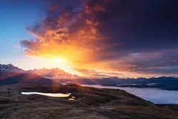 Raios solares sobre uma montanha e um lago.