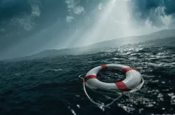 Uma boia salva-vidas à deriva em um mar agitado sob a luz solar que atravessa as nuvens.